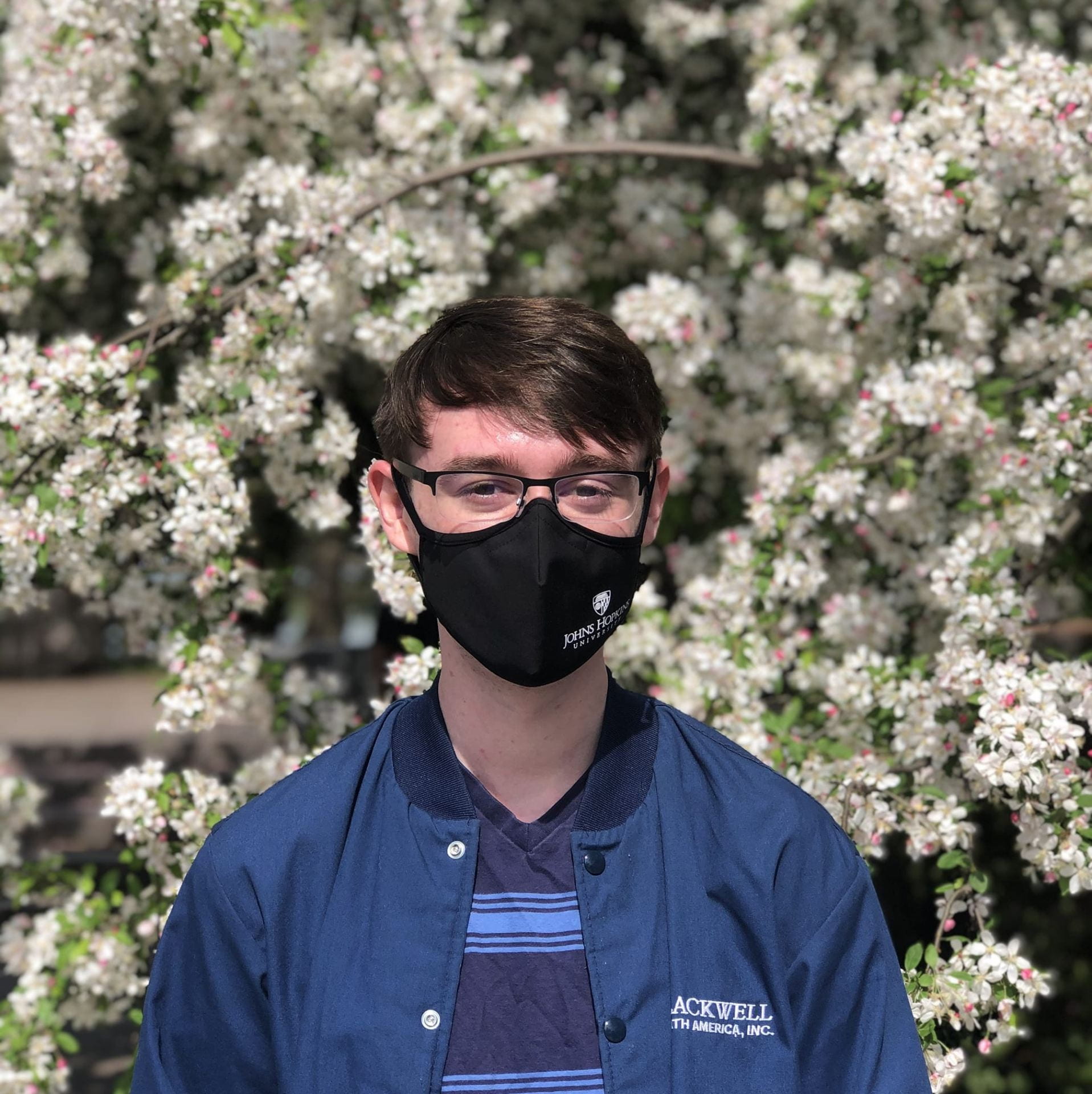 portrait of Fletcher Calcagno with face mask on in front of a flower tree