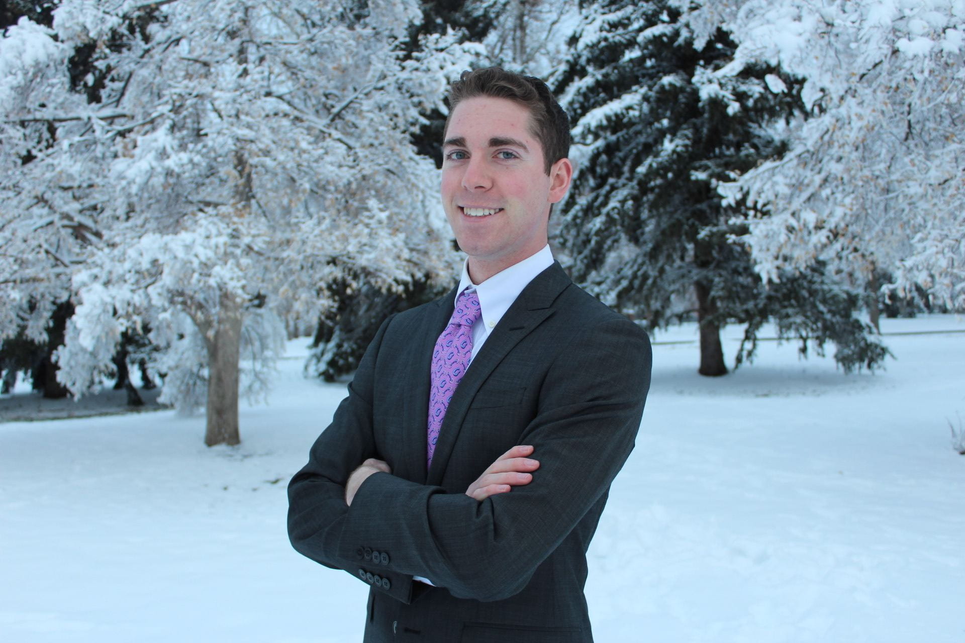 Tucker Hamilton in suit posing for portrait in a snowy field