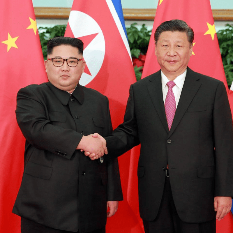 Kim Jong-un and Xi Jinping holding hands for press photos at a conference