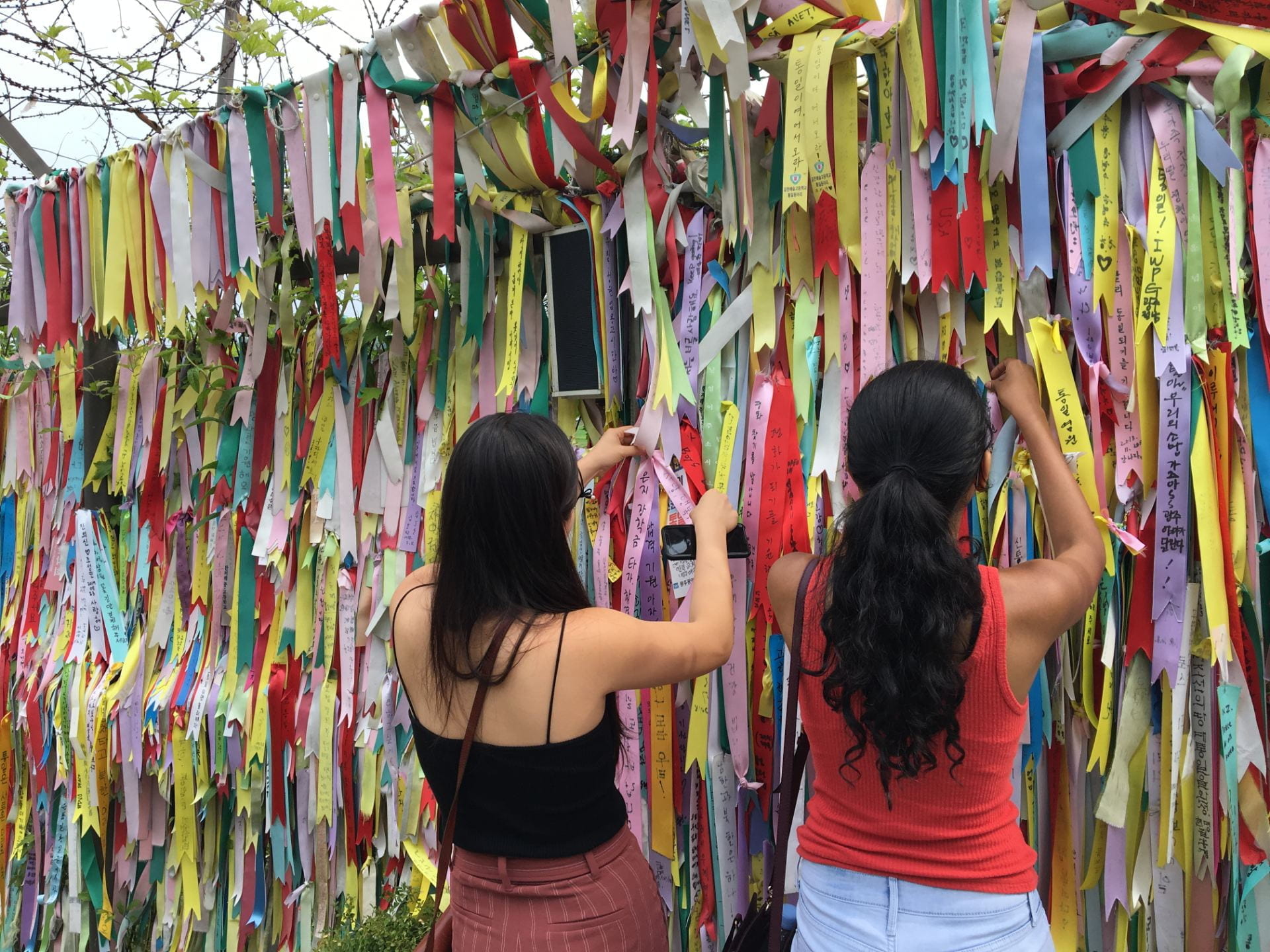 two girls looking through a wall of ribbons at the demilitarized zone in Korea