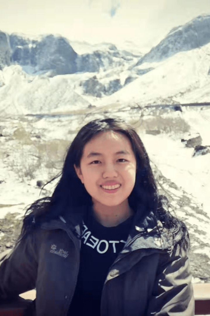 Yuchen Dai posing for picture with snowy mountains in the backdrop
