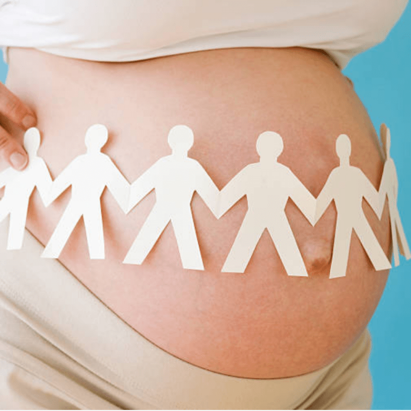 Pregnant belly with a cutout of people holding hands over the stomach
