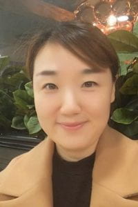 headshot of Juyeon Lee at a cafe with plants behind her