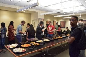 Asian Studies students gather around table with food for a reception event